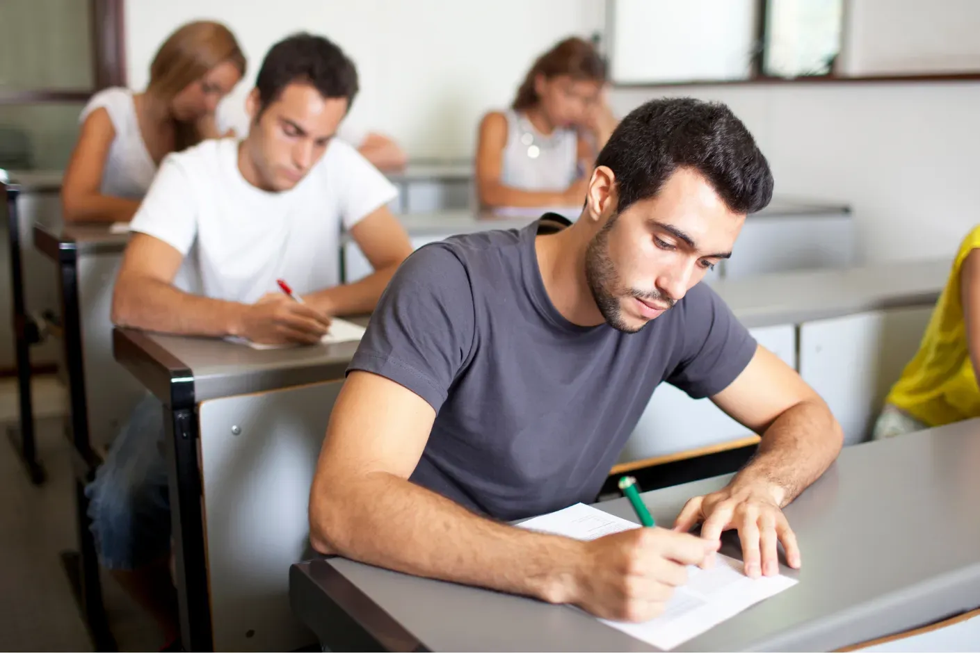 A student preparing for the GRE test with various study materials spread out on a desk.